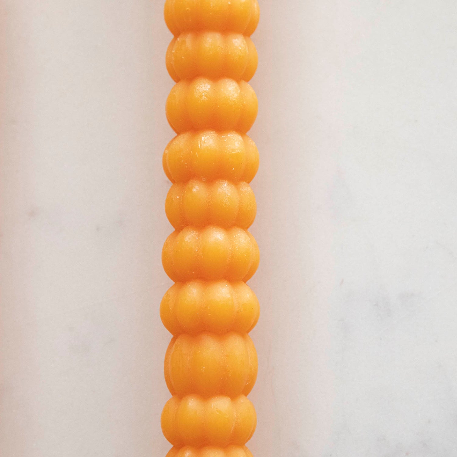 Close-up of the orange pumpkin taper candle. 