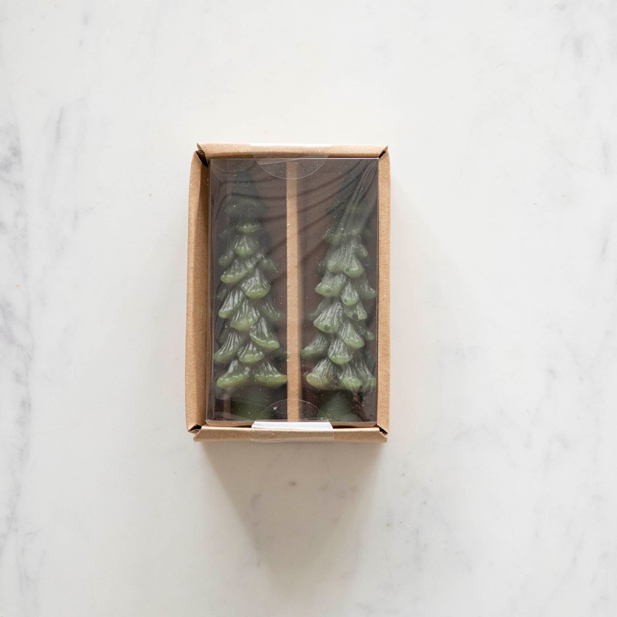 A set of two green tree-shaped taper candles placed in a box.