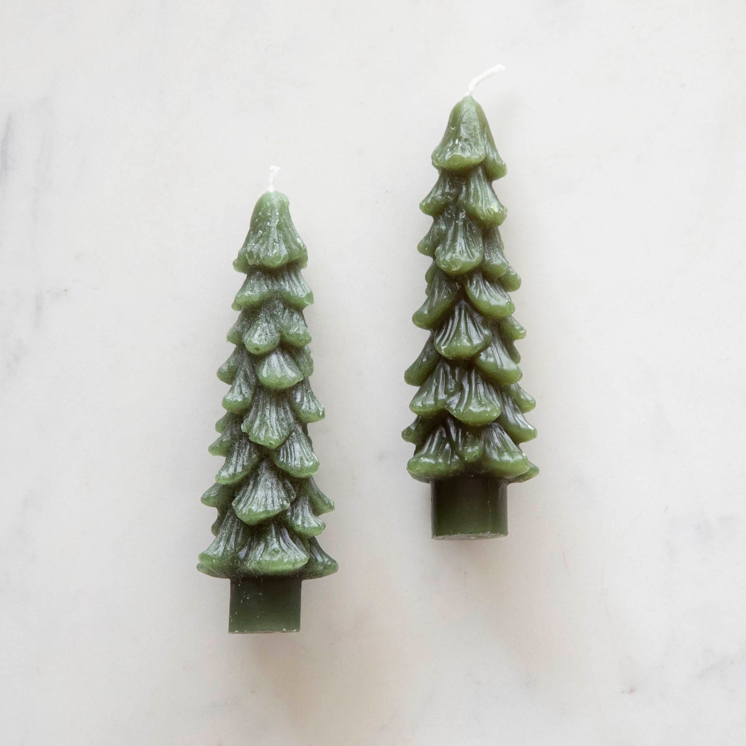 A set of two green tree-shaped taper candles. 