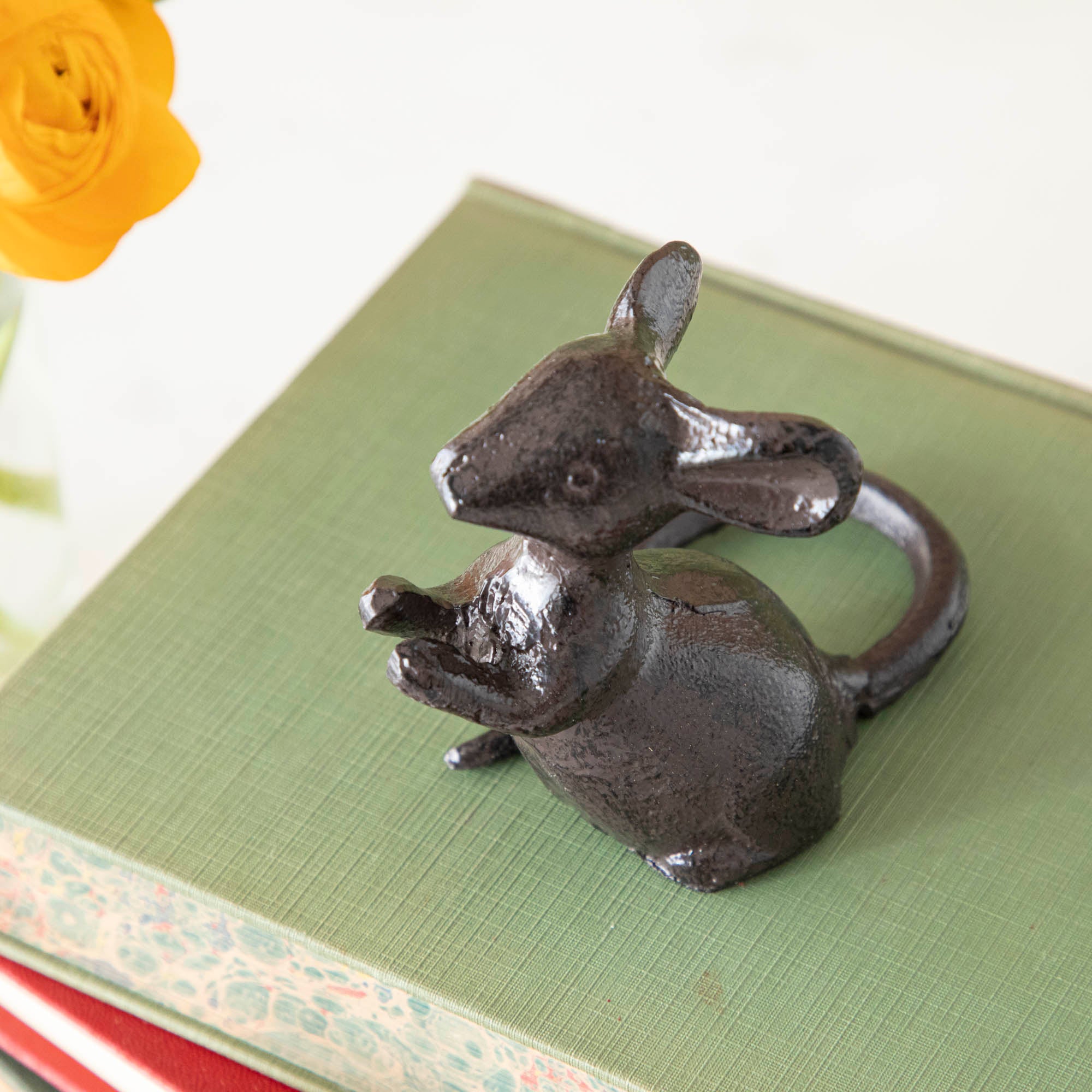 A cast iron mouse on top of a stack of books.