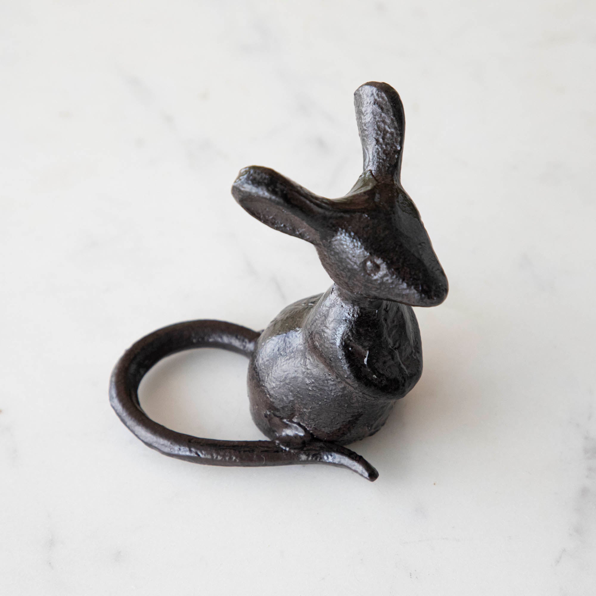 A cast iron mouse on a marble table.
