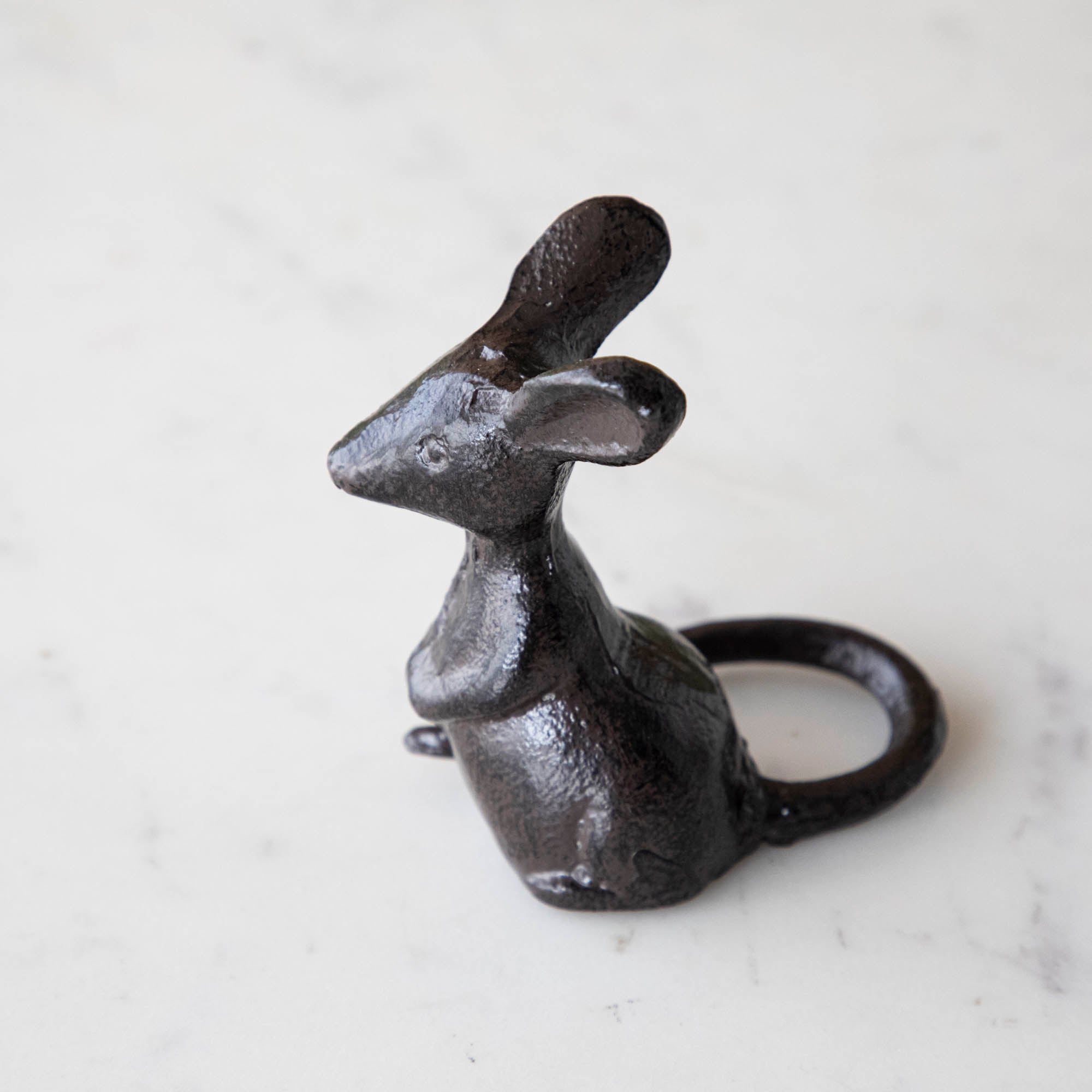 A cast iron mouse on a marble table.