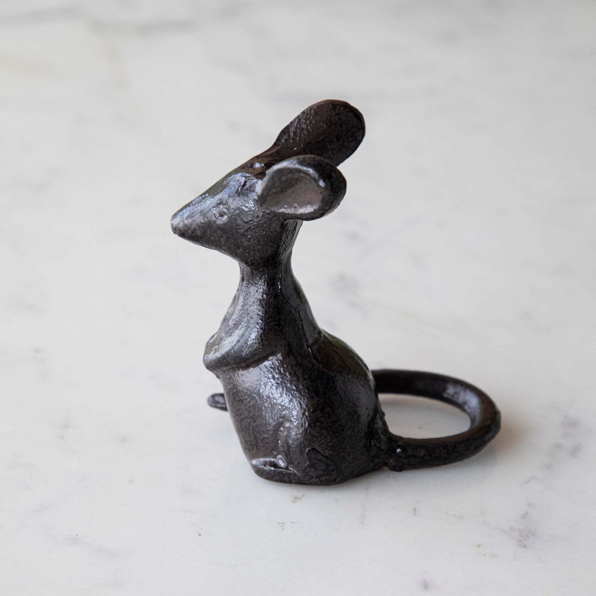 A cast iron mouse on a marble table.