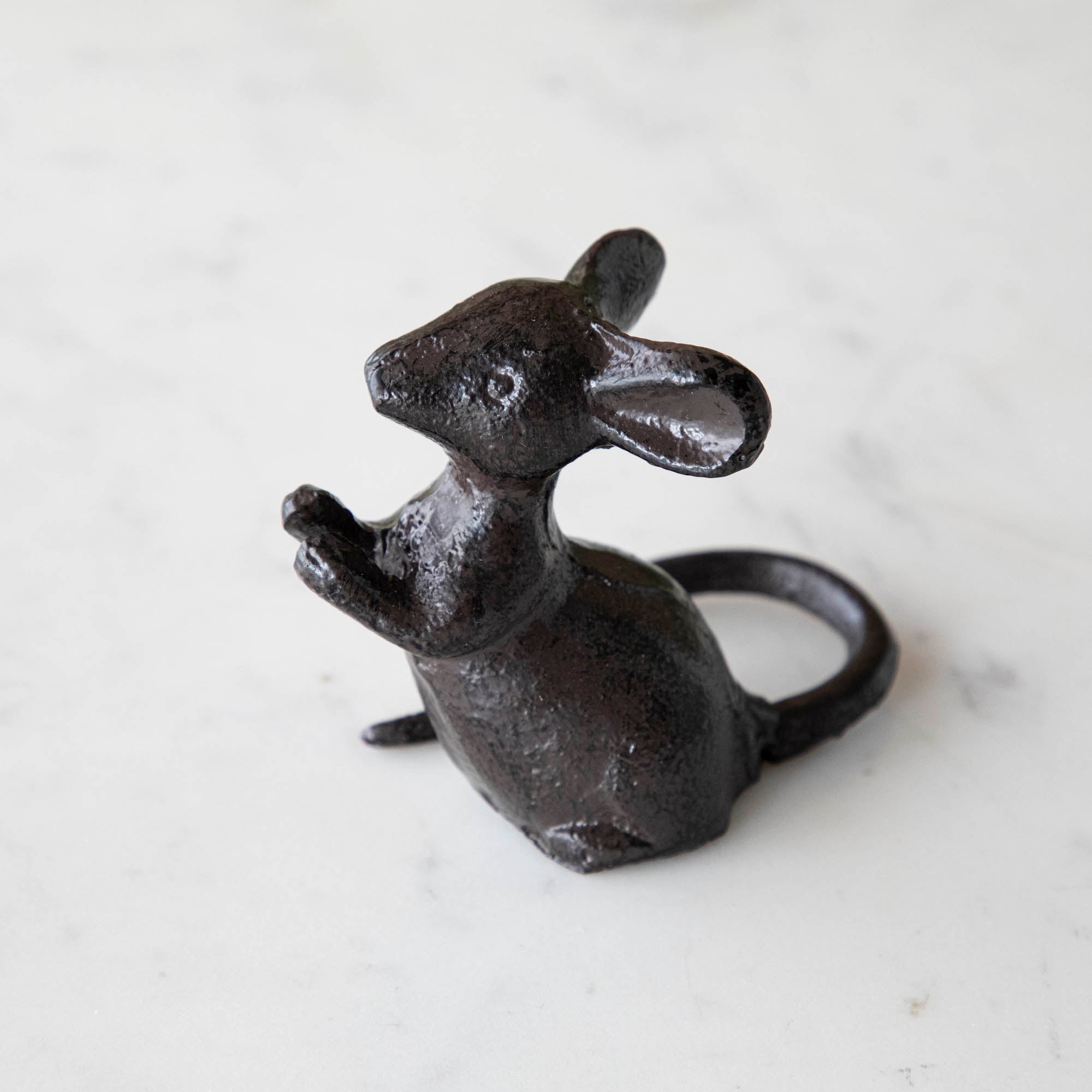 A cast iron mouse on a marble table.
