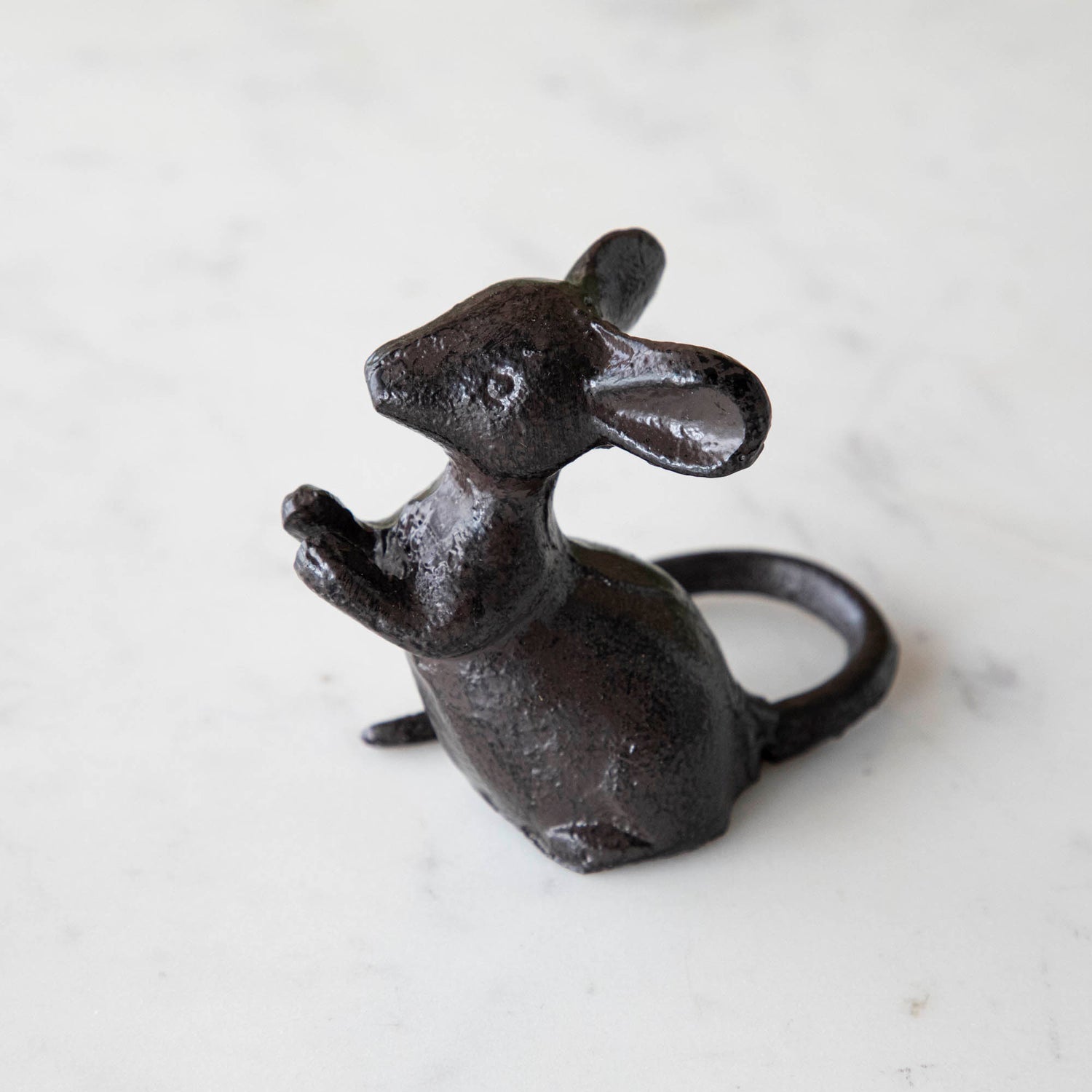 A cast iron mouse on a marble table.