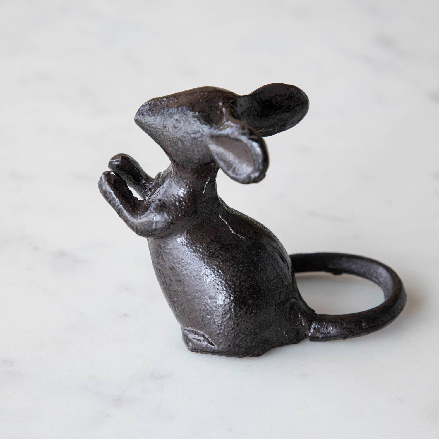 A cast iron mouse on a marble table.
