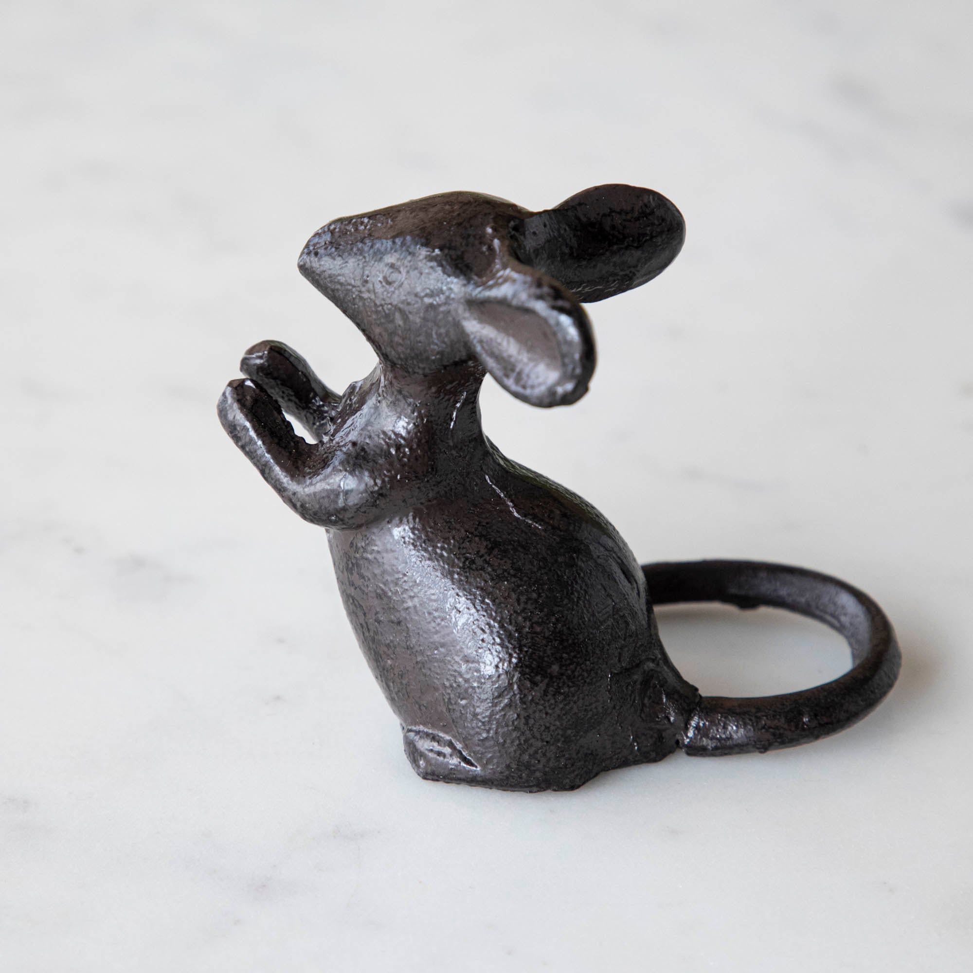 A cast iron mouse on a marble table.