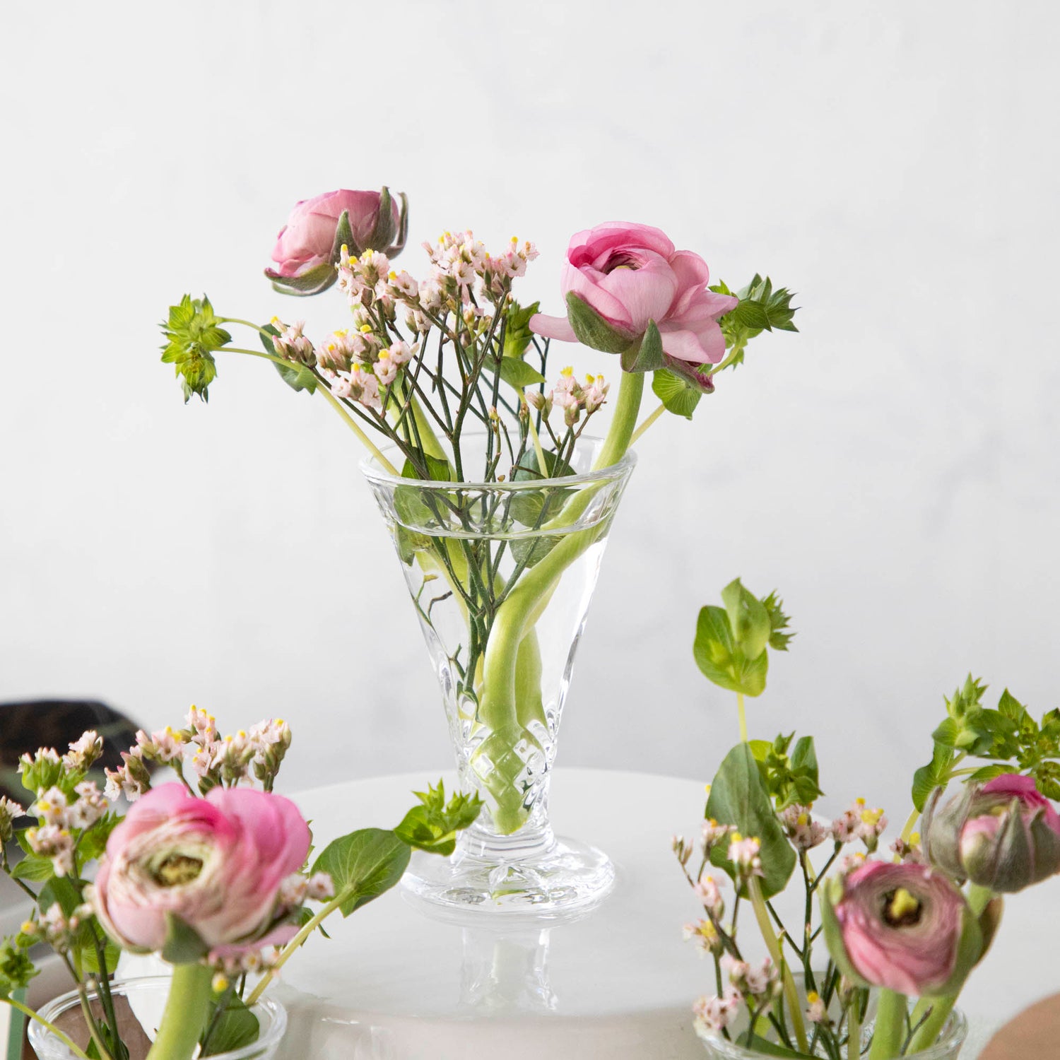A row of Dublin Crystal 5 Piece Bud Vase Set by Godinger with fresh flowers - perfect for adding a touch of beauty to any space.