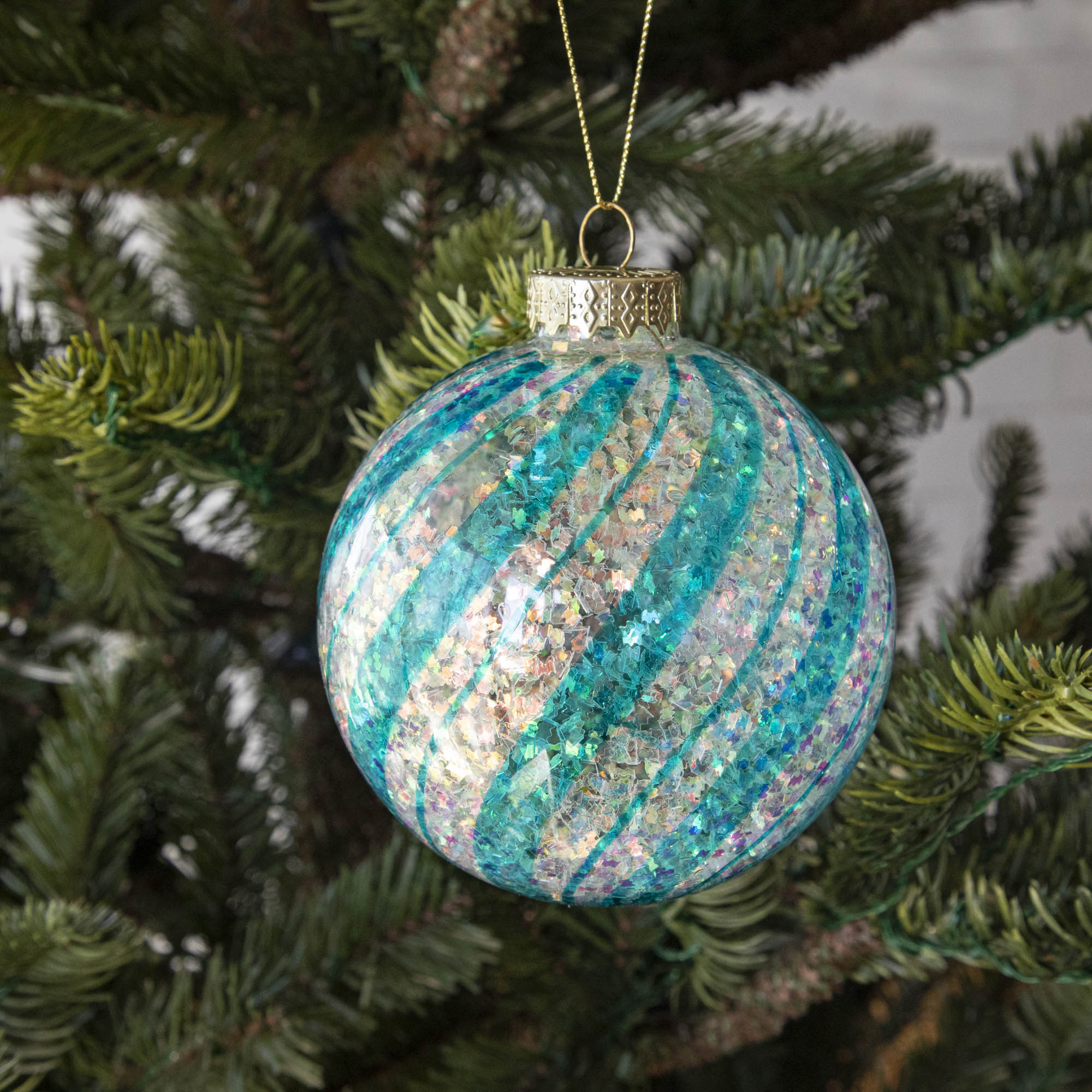 Blue & White Candy Striped Glitter ball ornament hanging in a tree