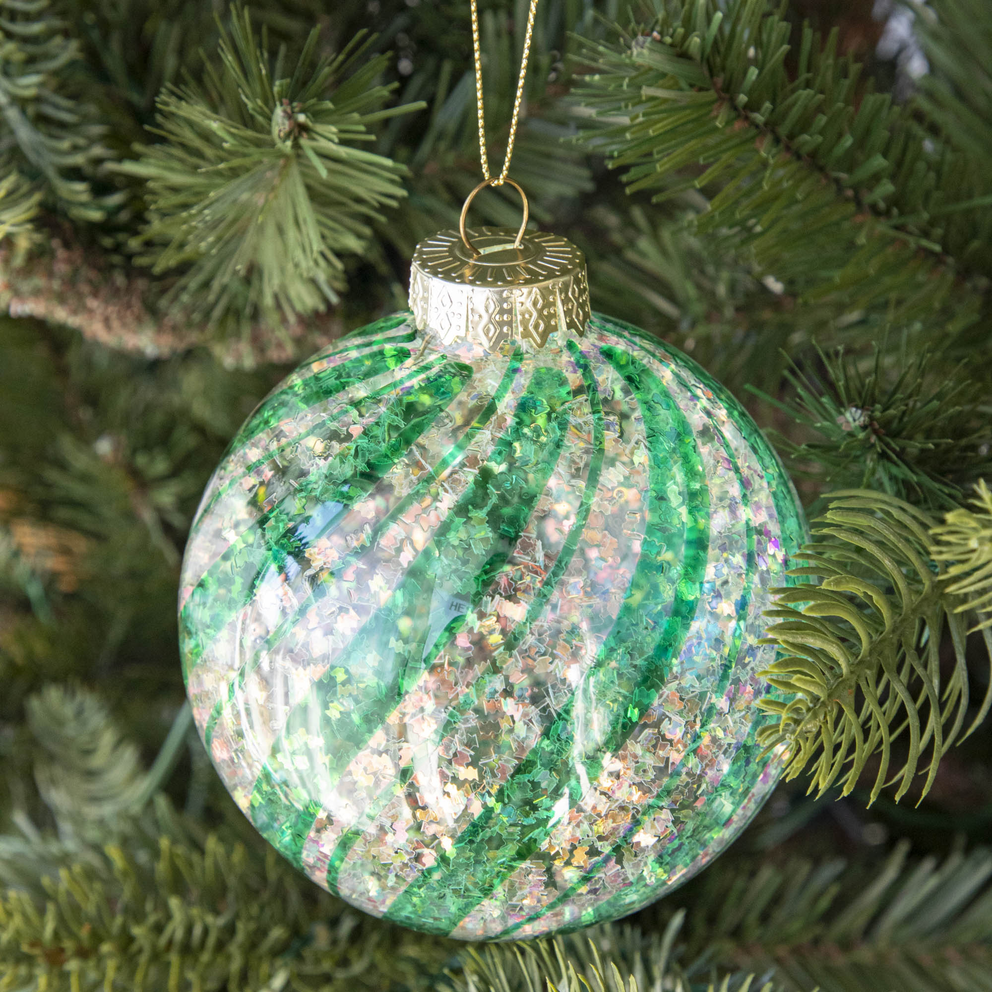 Teal & White Candy Striped Glitter ball ornament hanging in a tree