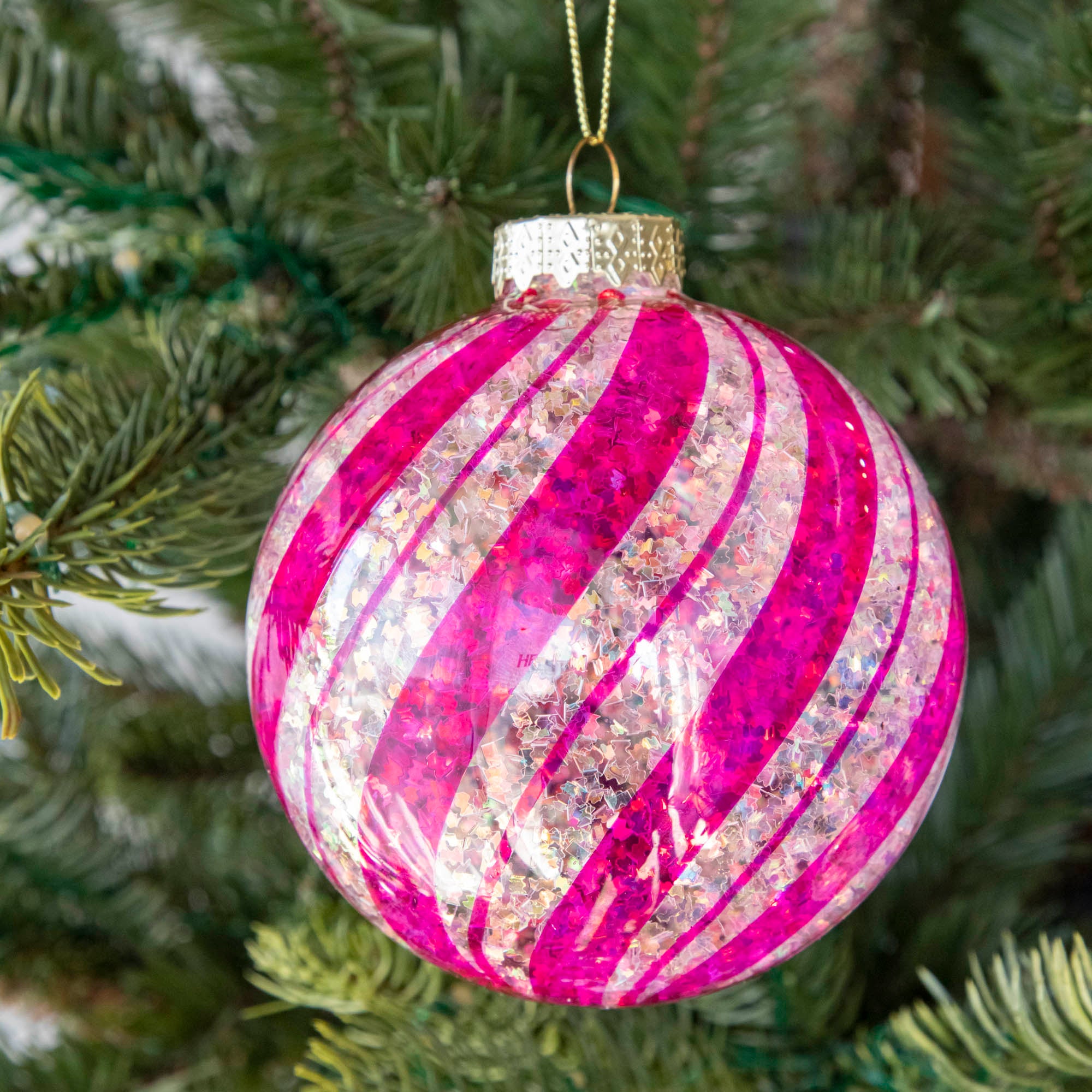 Pink & White Candy Striped Glitter ball ornament hanging in a tree