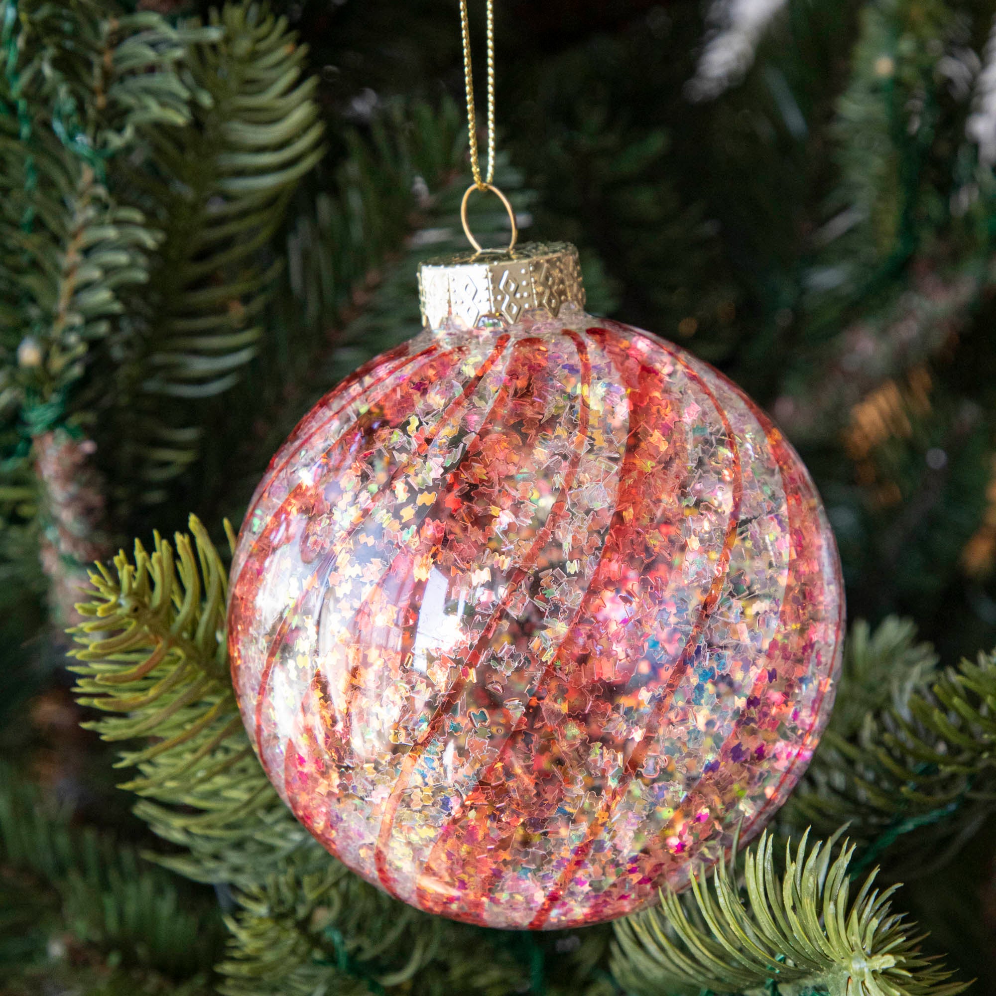Orange & White Candy Striped Glitter ball ornament hanging in a tree