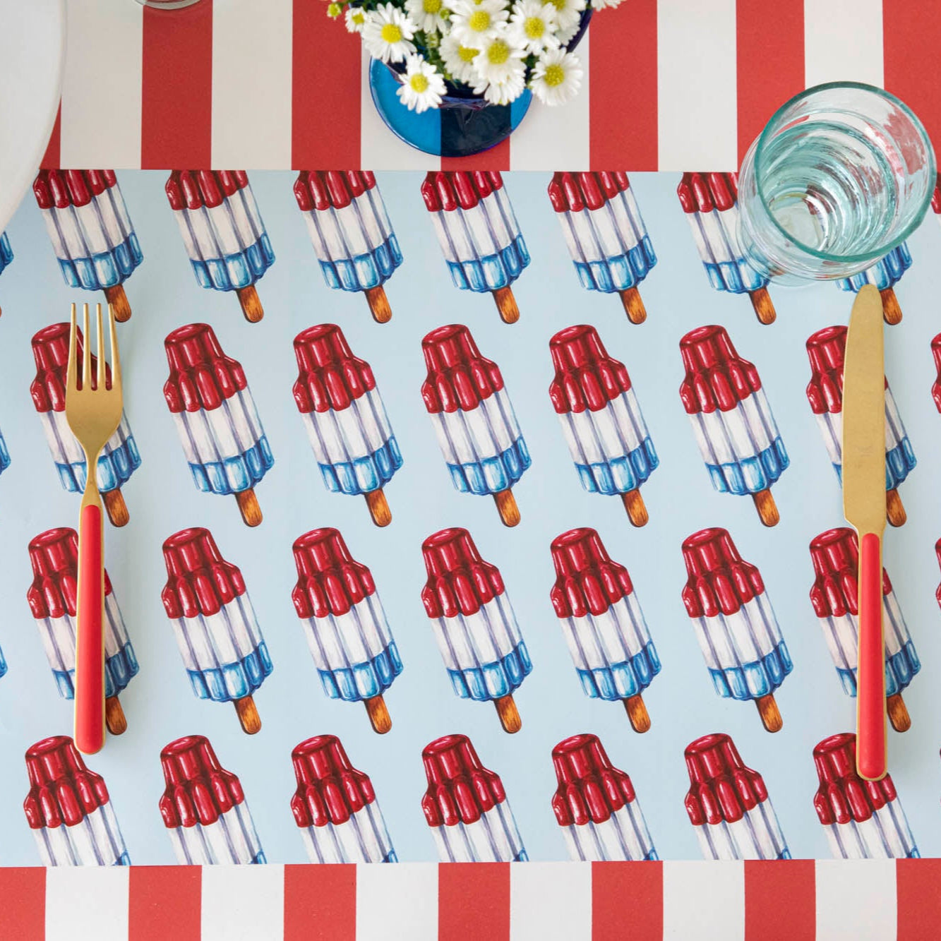 Rocket Pop Placemat with red & gold flatware on top, on the Red Classic Stripe Runner.