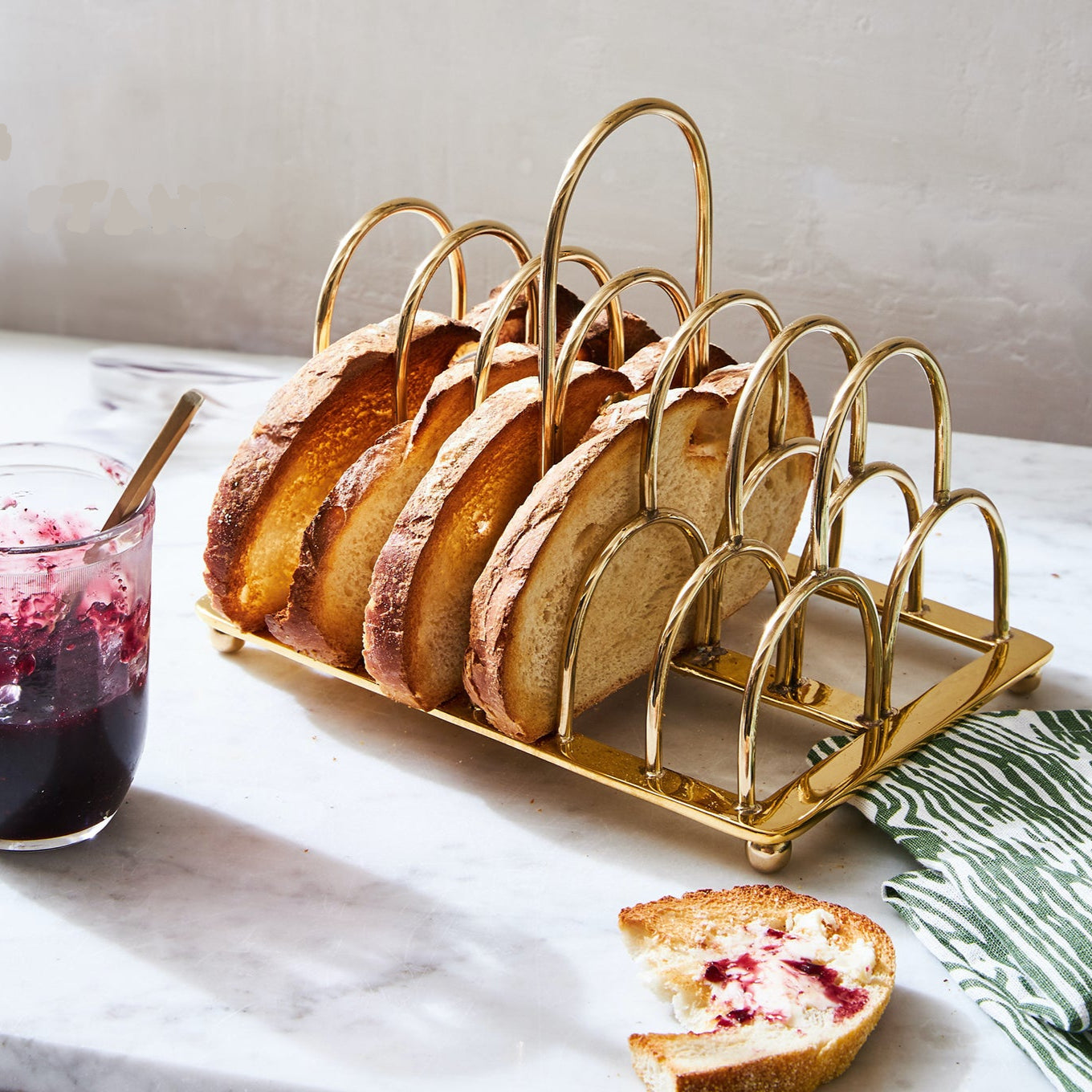 A brass Correspondence Stand with slices of toast in it and a jar of jelly next to it.