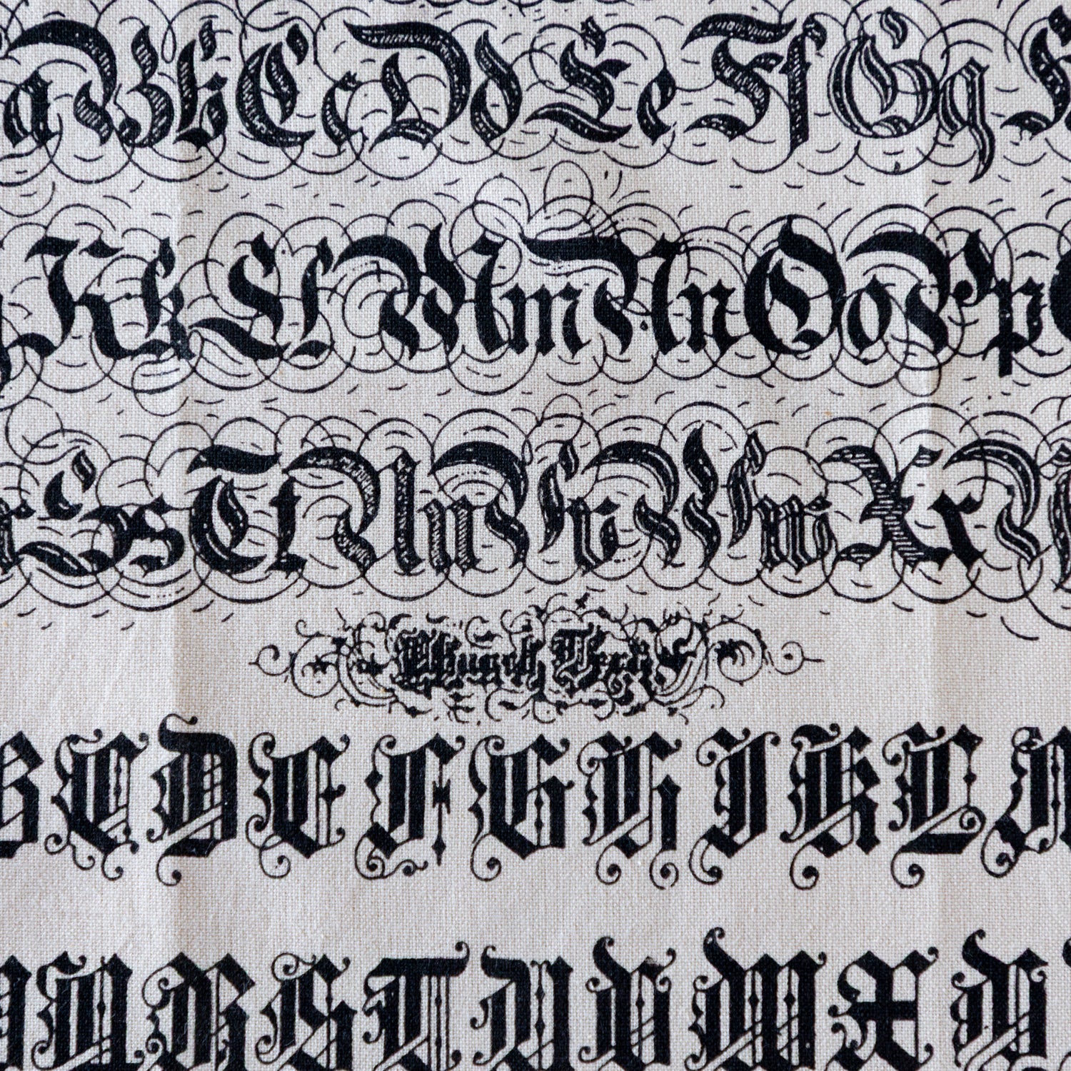 A close up of the Old English Tea Towel featuring the alphabet and numbers in old english font.