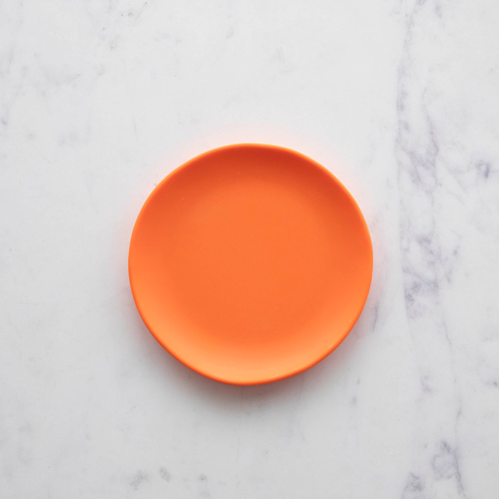 A 6" Rainbow Melamine Plate by Glitterville on a marble surface.