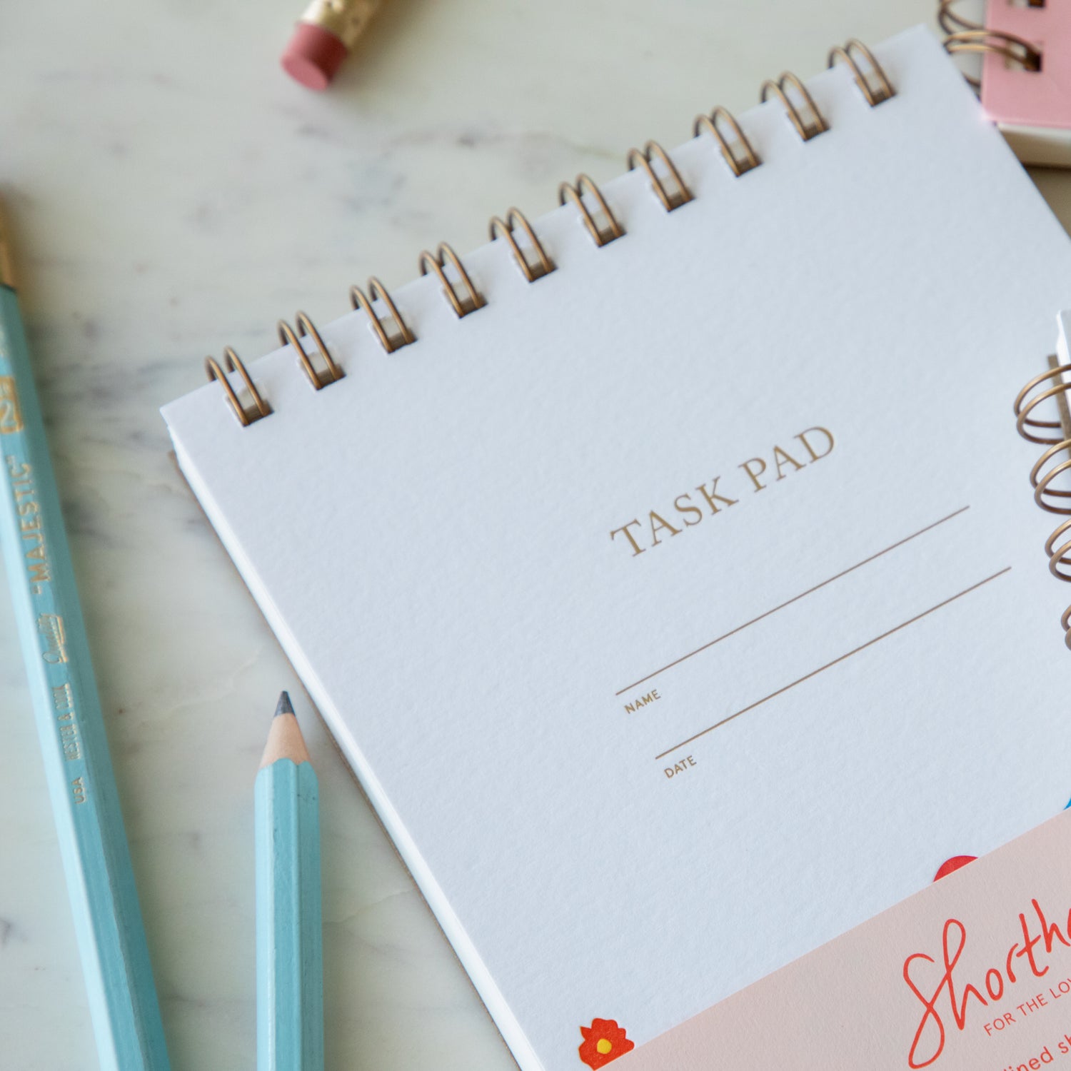 A close up of the Super Blooms Task Pad Notepad showing the lines for a name and date and spiral binding.