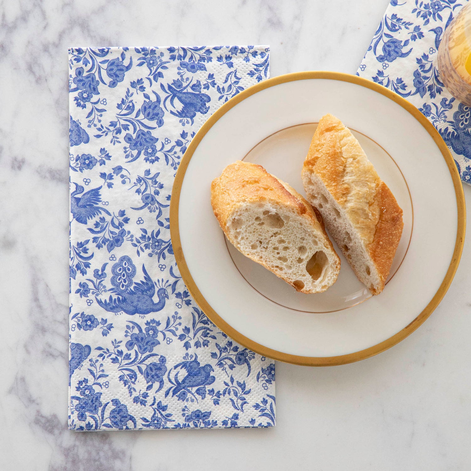 A plate of bread on top of a Blue Regal Peacock Guest Napkin by Hester & Cook.