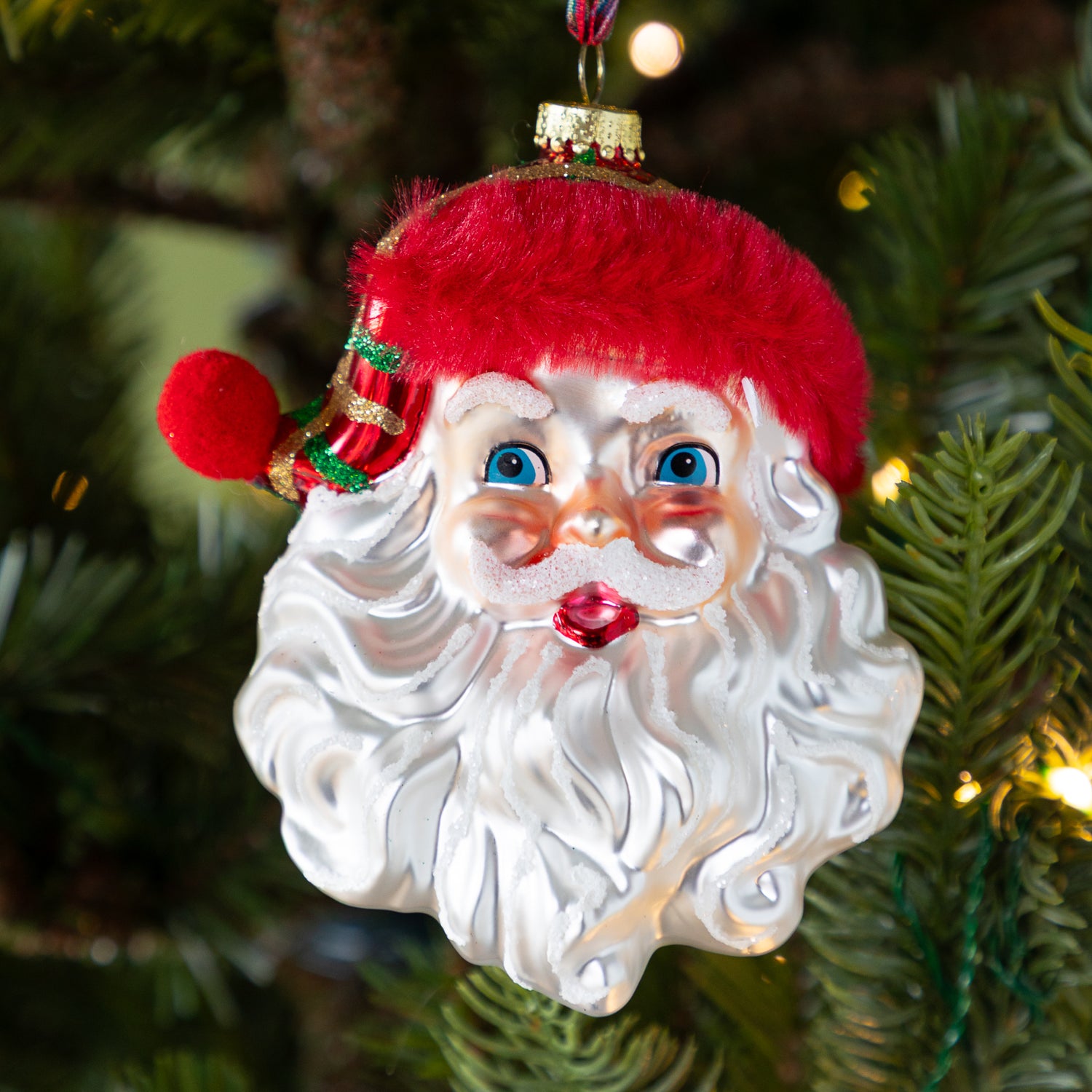 Decorative red hat Santa Claus ornament on a Christmas tree.