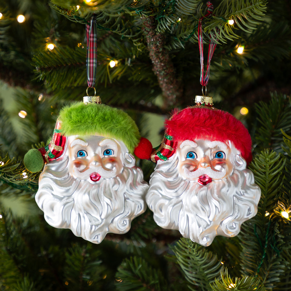 Plaid Santa Head Ornaments in red and green against a lit up Christmas tree.