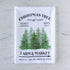 Tea towel with Christmas tree design and text on a marble surface.