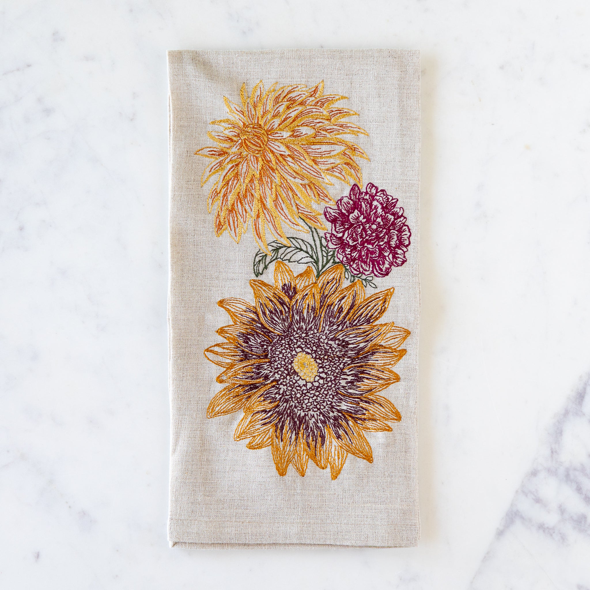 Floral embroidered autumn flowers towel on a marble surface.