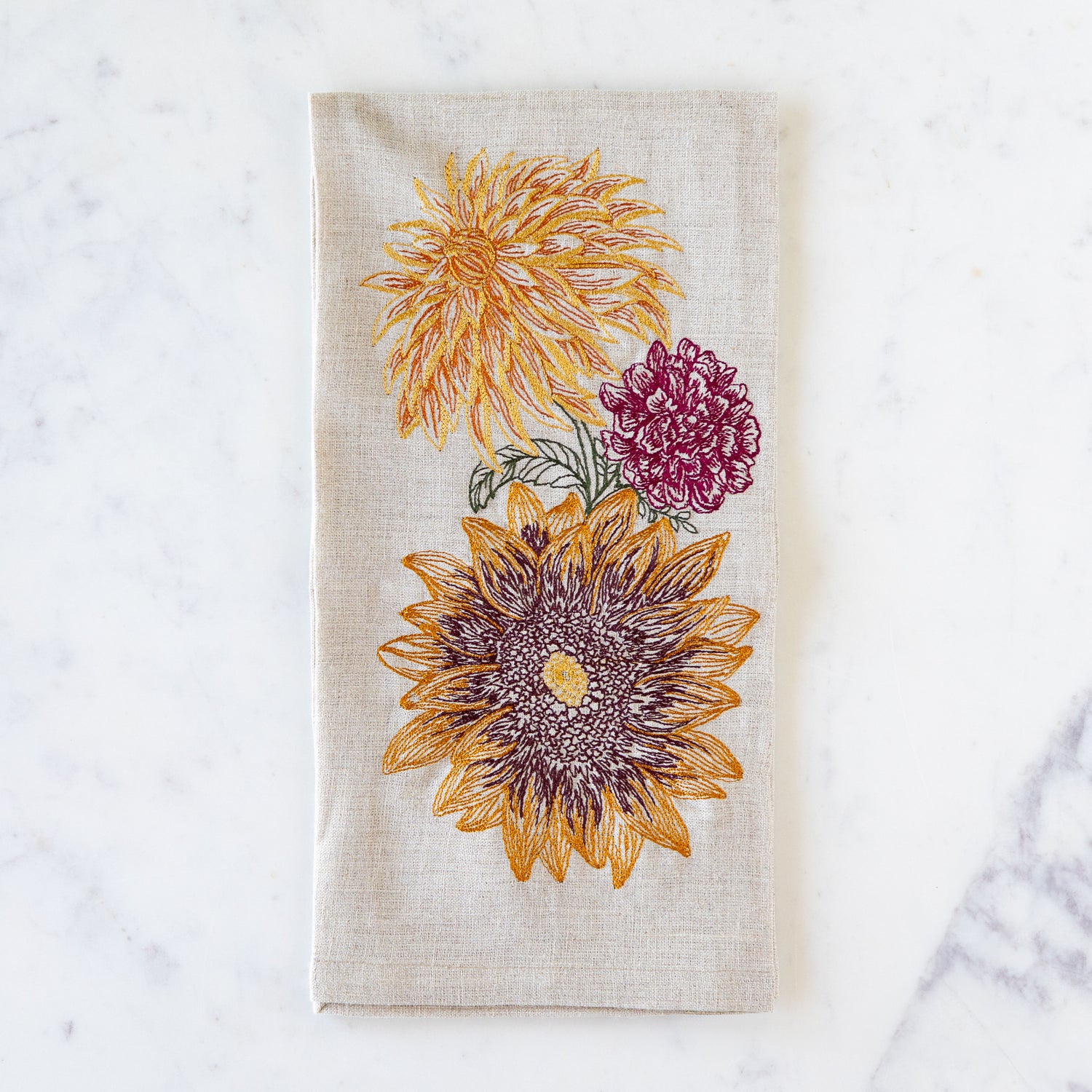 Floral embroidered autumn flowers towel on a marble surface.