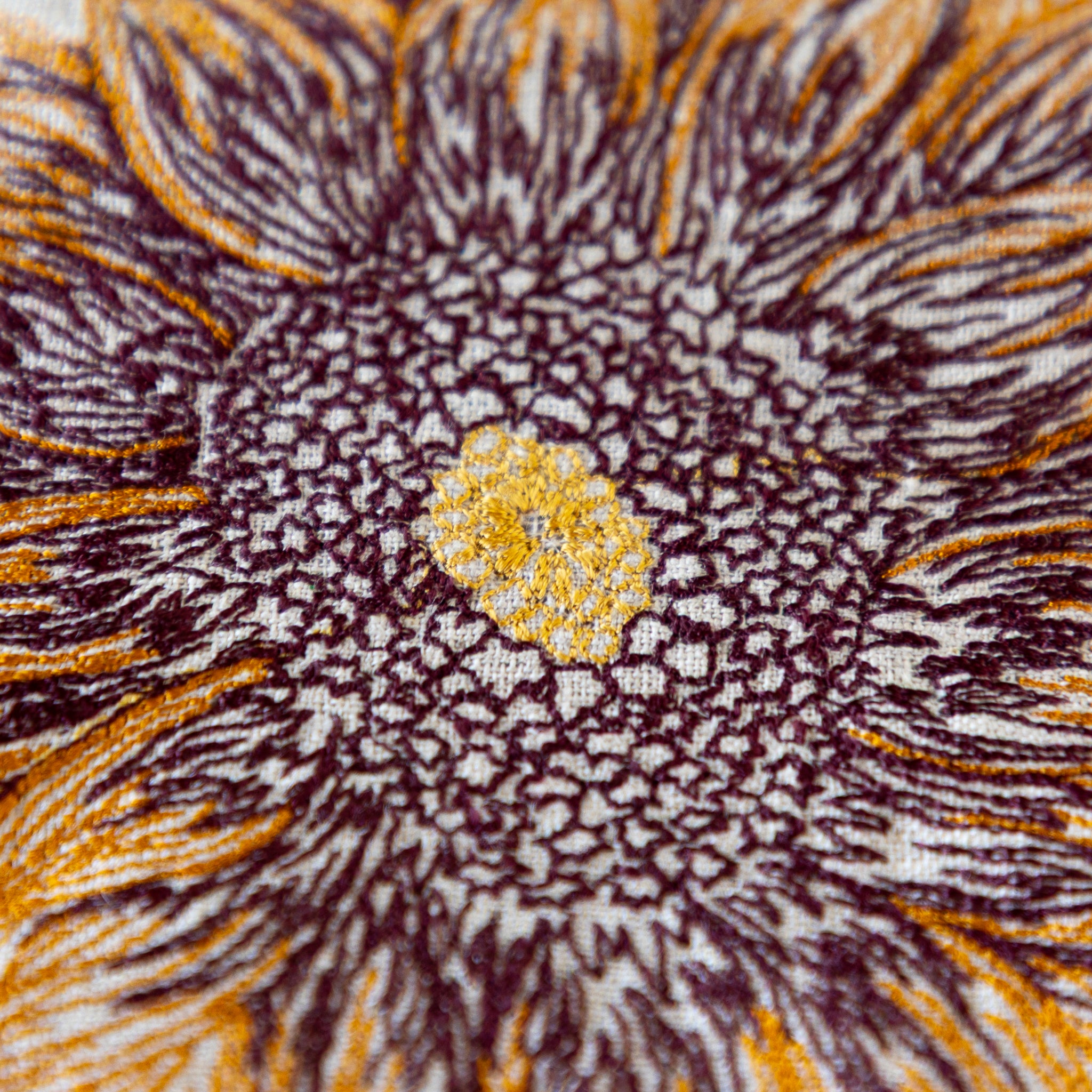 Close-up of an embroidered sunflower pattern with brown, yellow, and white colors.