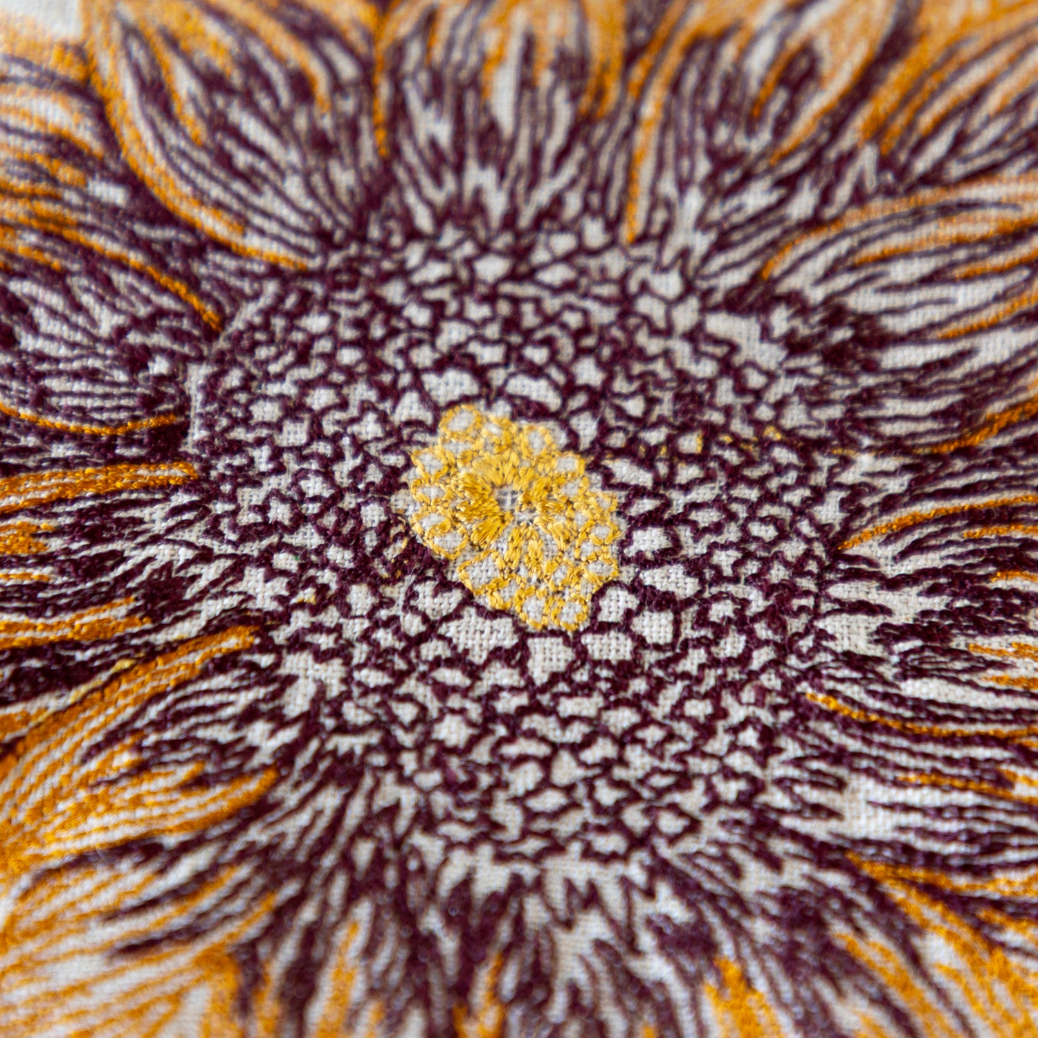 Close-up of an embroidered sunflower pattern with brown, yellow, and white colors.