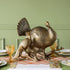 A bronze metal turkey on a branch decoration, placed on a dining table with green wall in the background.