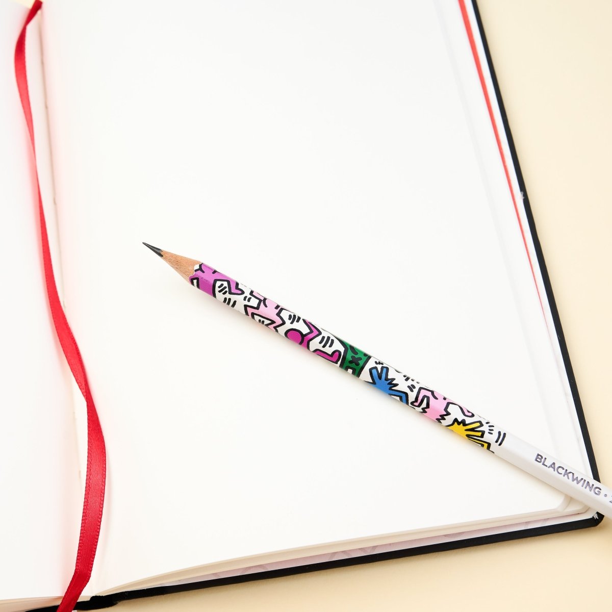Blank page from the Blackwing notebook with a Blackwing pencil that has artwork by Keith Haring printed on it. 