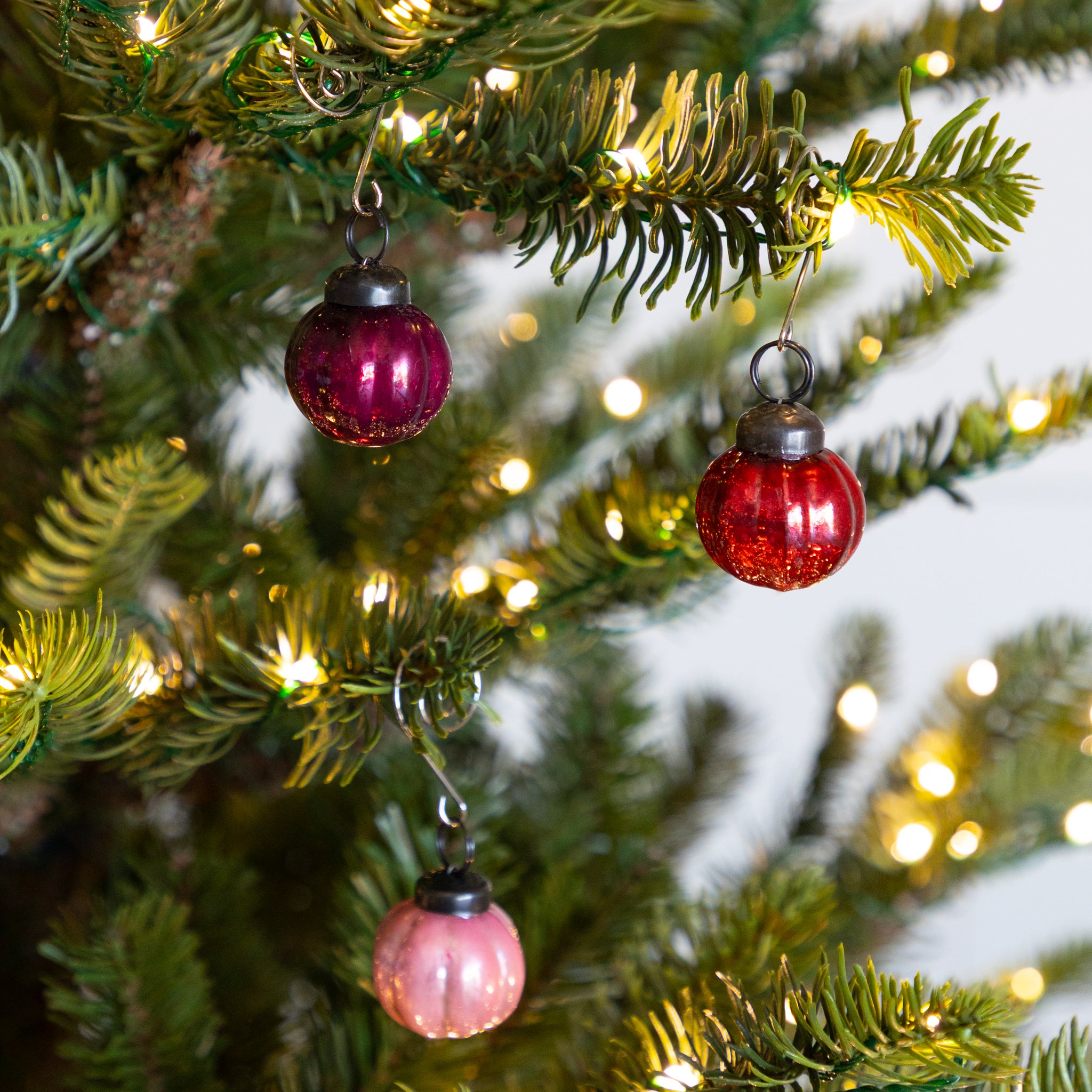 Red and pink glass Multi Color Mercury Glass Ornaments on a Christmas tree with lights.