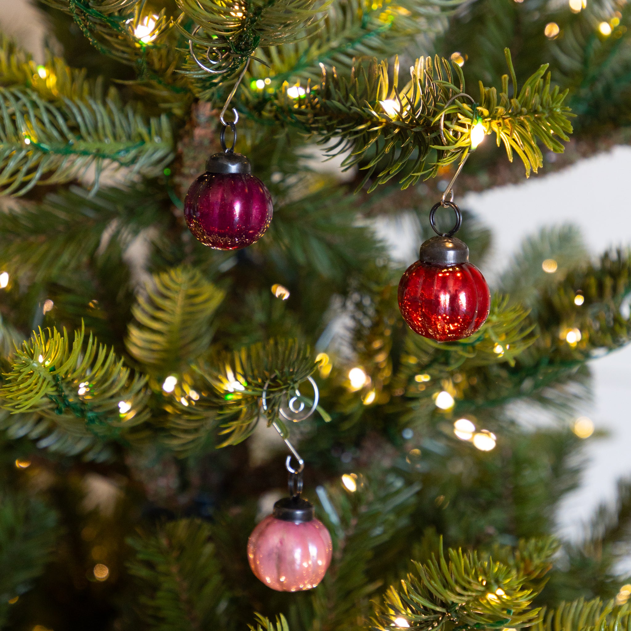 Red and pink glass Multi Color Mercury Glass Ornaments on a Christmas tree with lights.