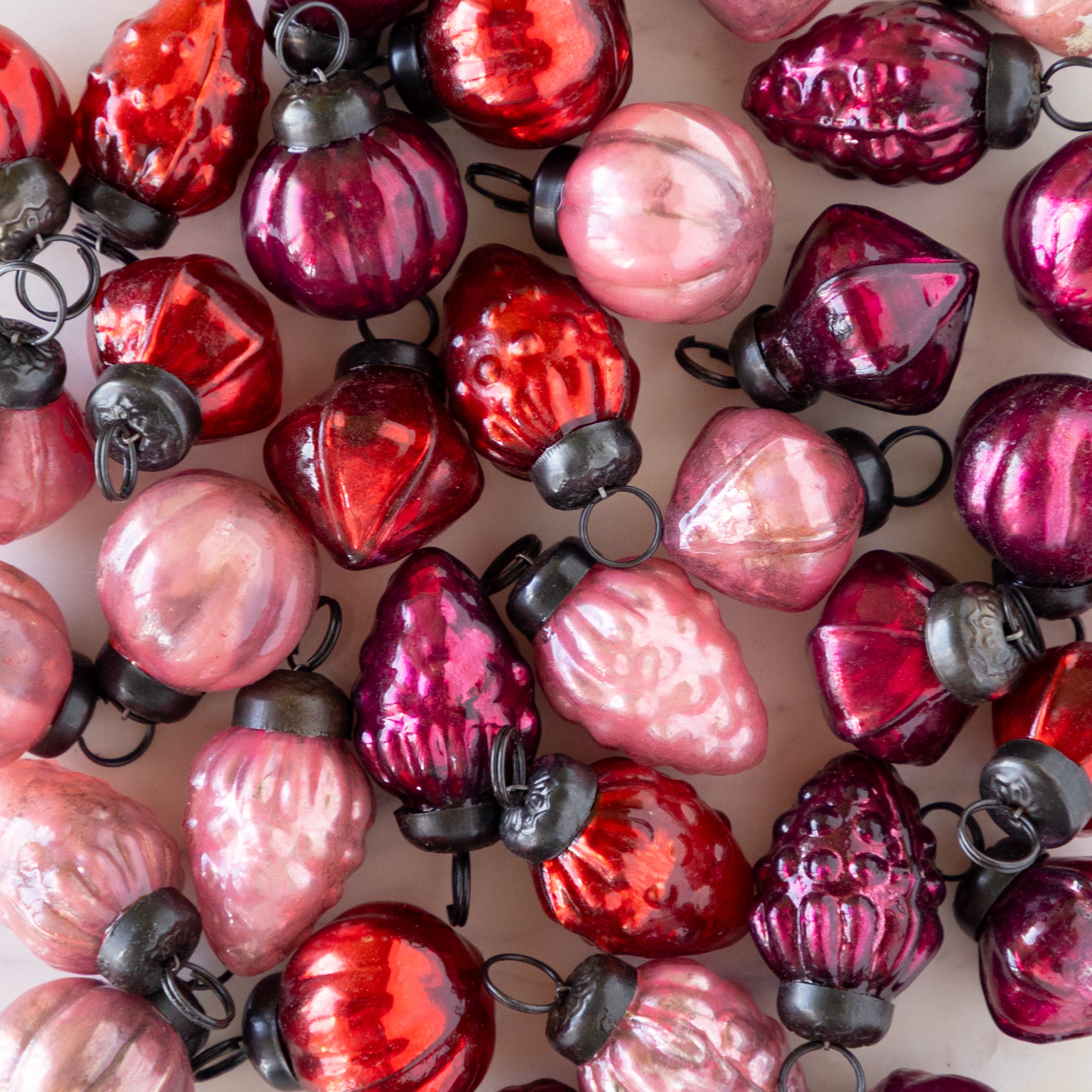 Close-up of red and pink Multi Color Mercury Glass Ornaments on a table.