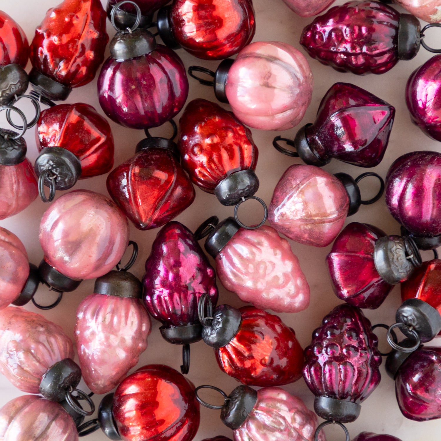 Close-up of red and pink Multi Color Mercury Glass Ornaments on a table.