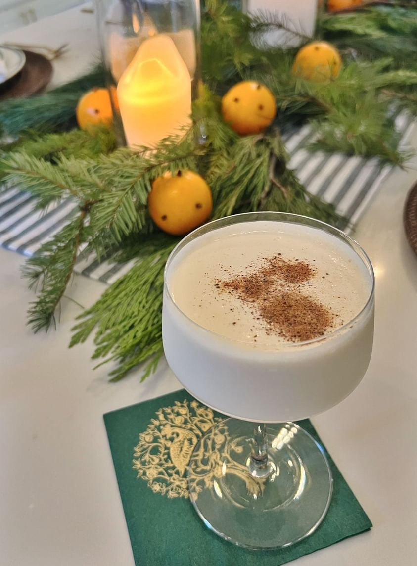 Cocktail with cinnamon garnish on a table with Partridge in a Pear Tree Beverage Napkin.