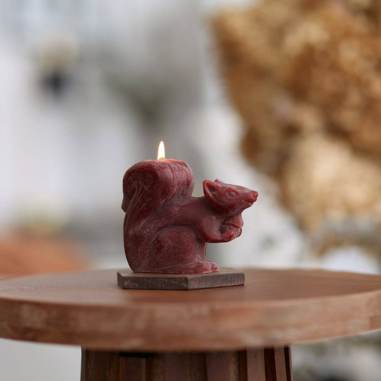 Squirrel-shaped candle on a wooden surface with a blurred natural background