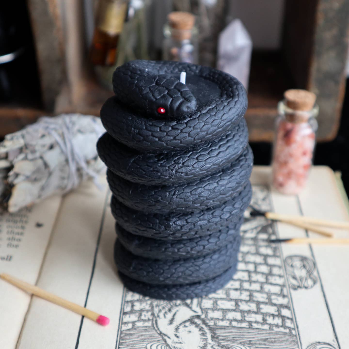 Pillar candle that looks like it has a black snake wrapped around it.