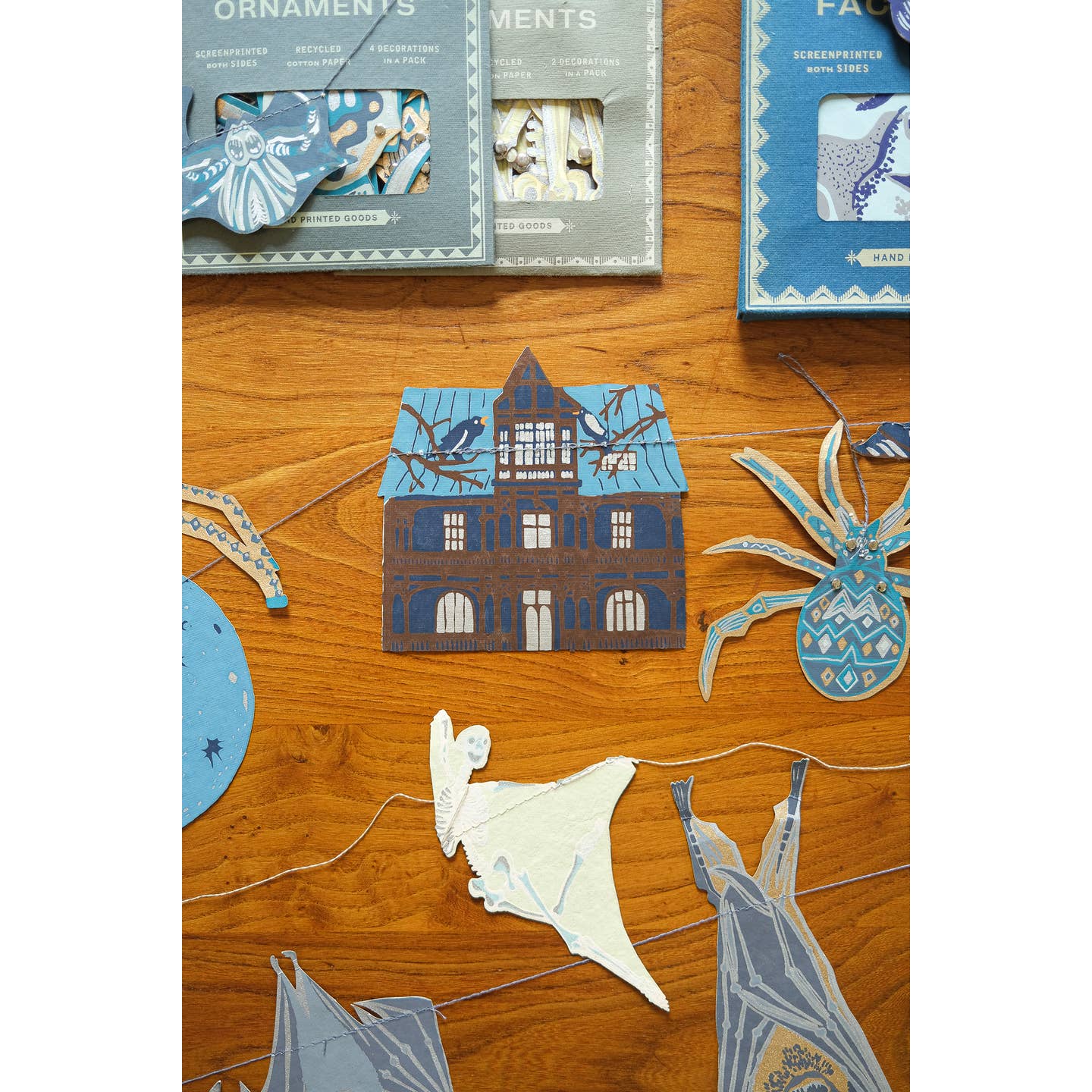 Package of the Haunted House sewn garland on a table surrounded by the garland.