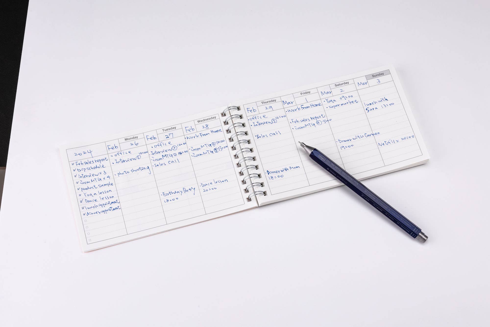 Small notebook with handwritten notes on a white surface with a pen next to it.
