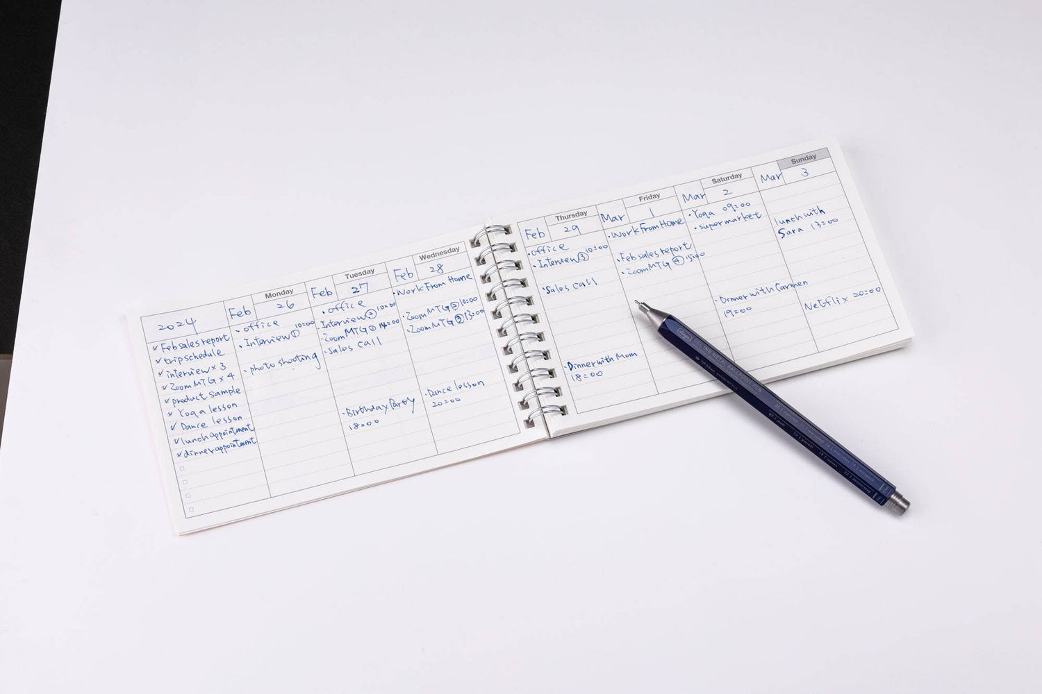 Small notebook with handwritten notes on a white surface with a pen next to it.