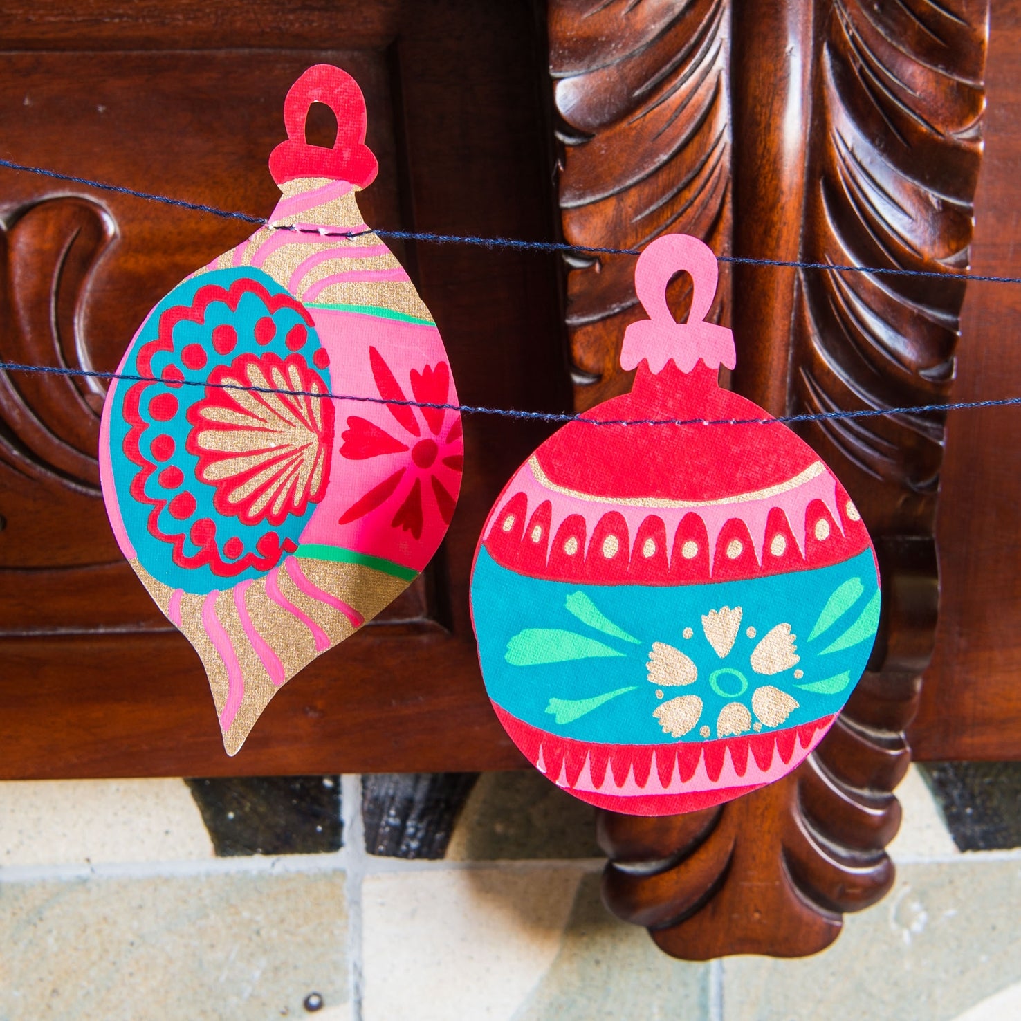 Decorative Christmas ornaments with colorful patterns hanging on a wooden surface.