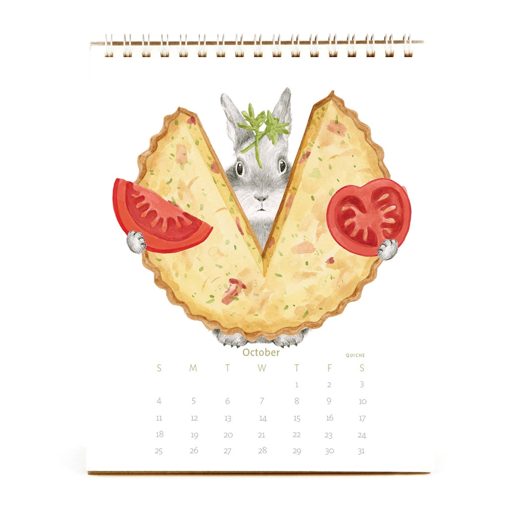 2026 Dear Hancock Bunny Calendar hiding behind a quiche holding tomatoes.