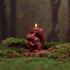 Squirrel-shaped candle on a wooden stump with a blurred forest background