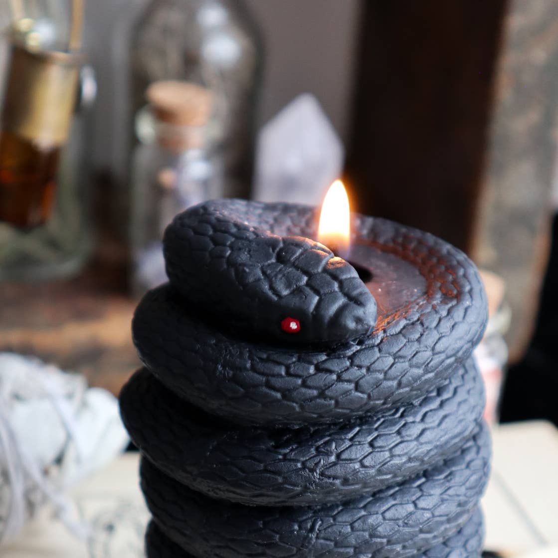 Pillar candle that looks like it has a black snake wrapped around it.
