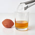 Football-shaped ice cube tray next to a football-shaped ice cube going into a glass of liquid.