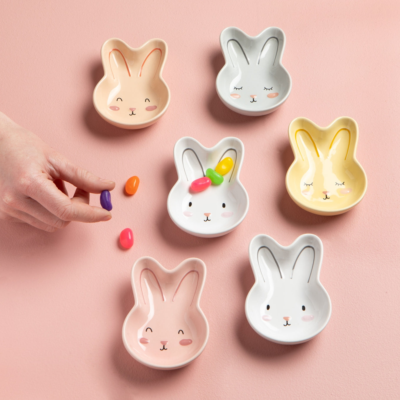 Six bunny-shaped ceramic bowls on a pink background.