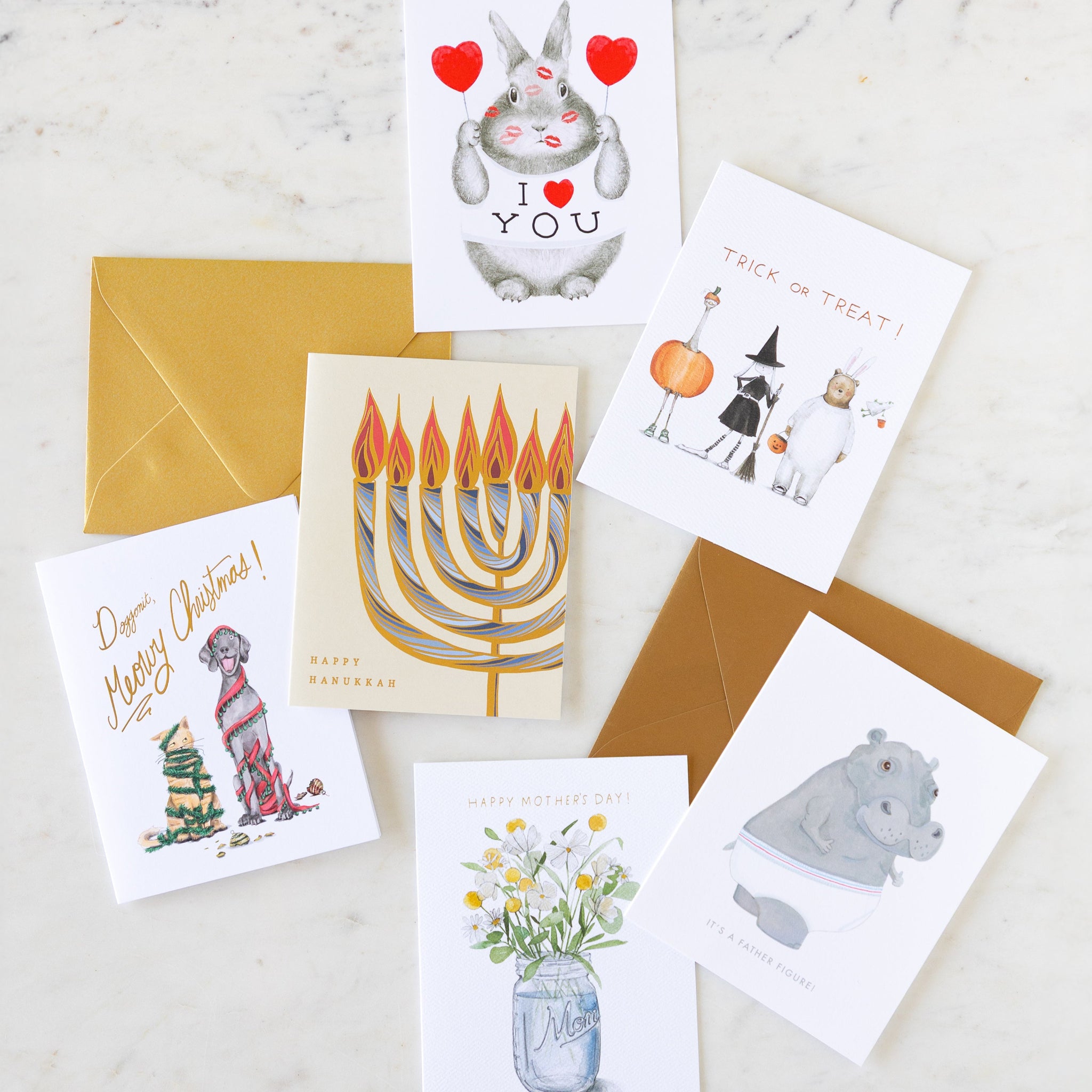 Six holiday cards arranged on a table with two envelopes.