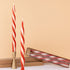 Red and white twisted candles with a gold holder on a beige background.