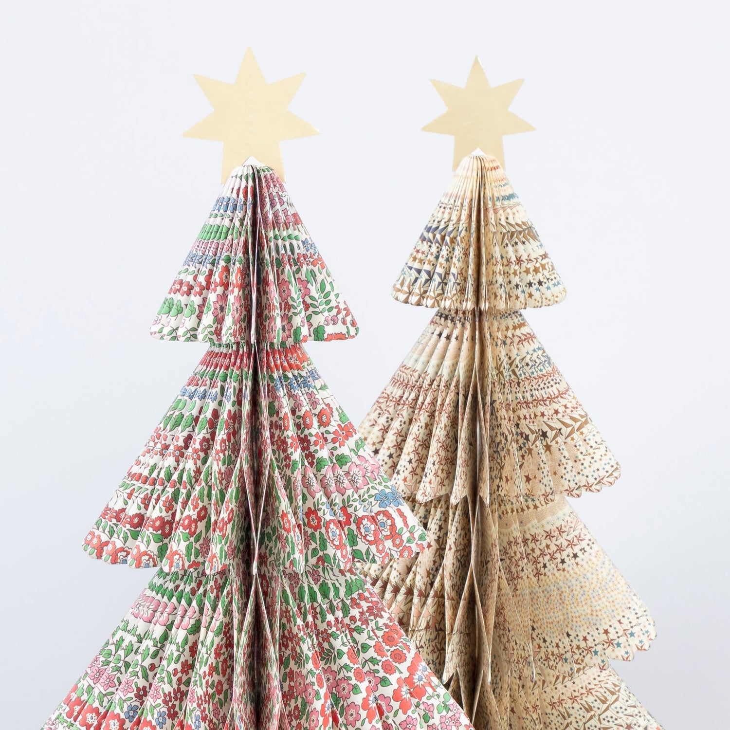 Two paper Christmas trees with star toppers on a white background. 